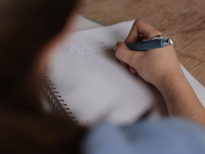 Person schreibt Mathematikaufgaben in ein Notizbuch